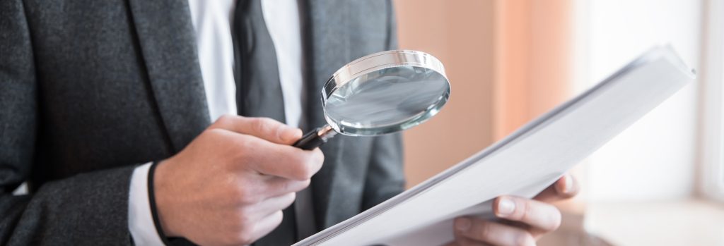 business man holding magnifier and document